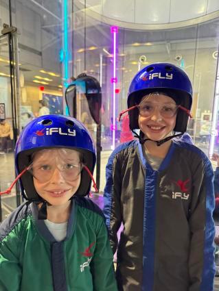 2 kids posing for a photo wearing helmets for iFly