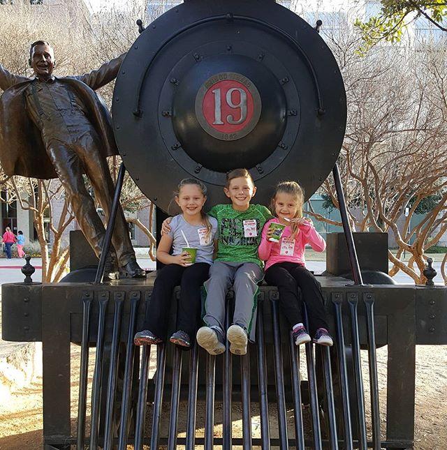 3 children sitting on a sculpture posing for a photo