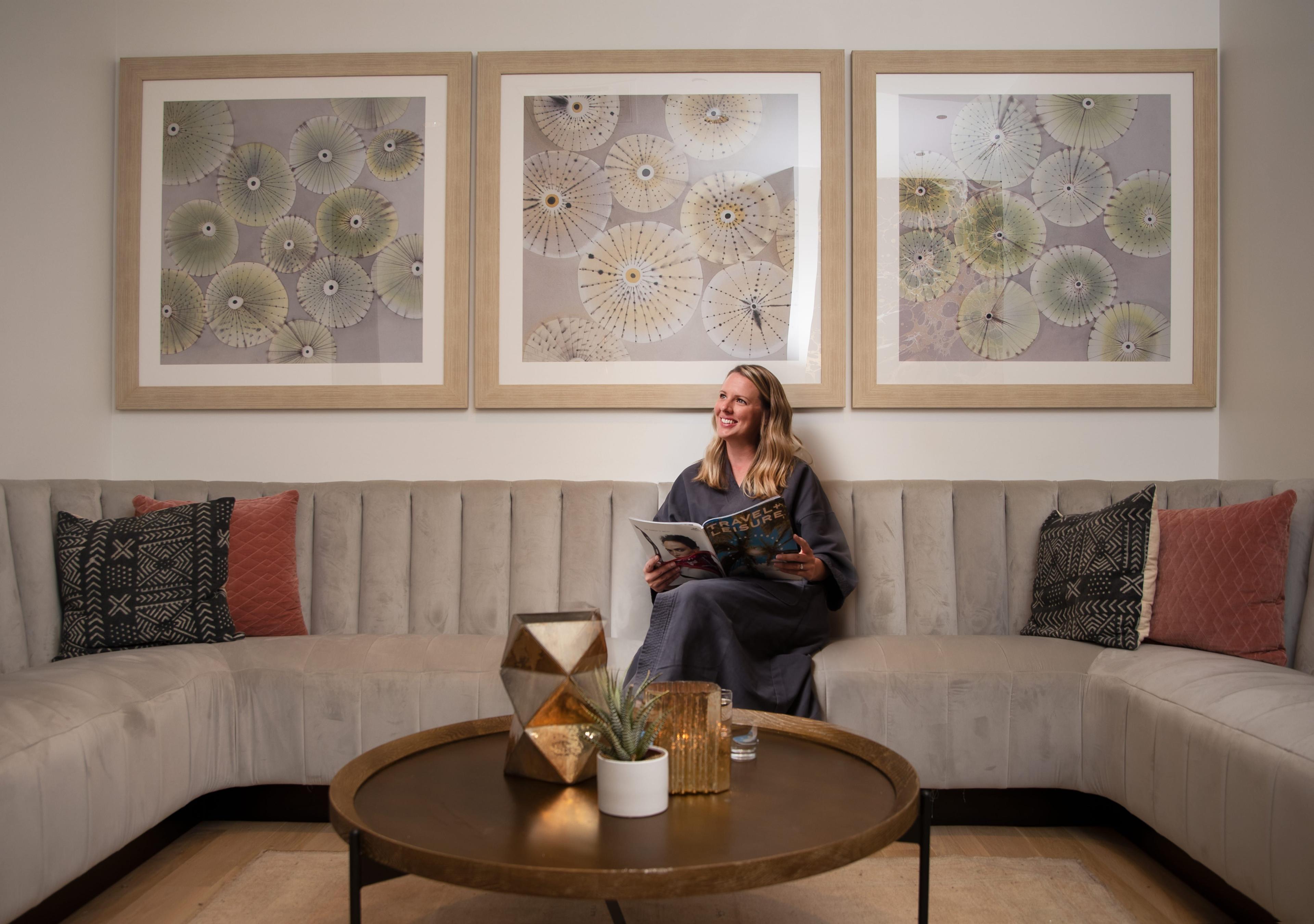 A woman in the spa waiting area with a robe on, reading a magazine