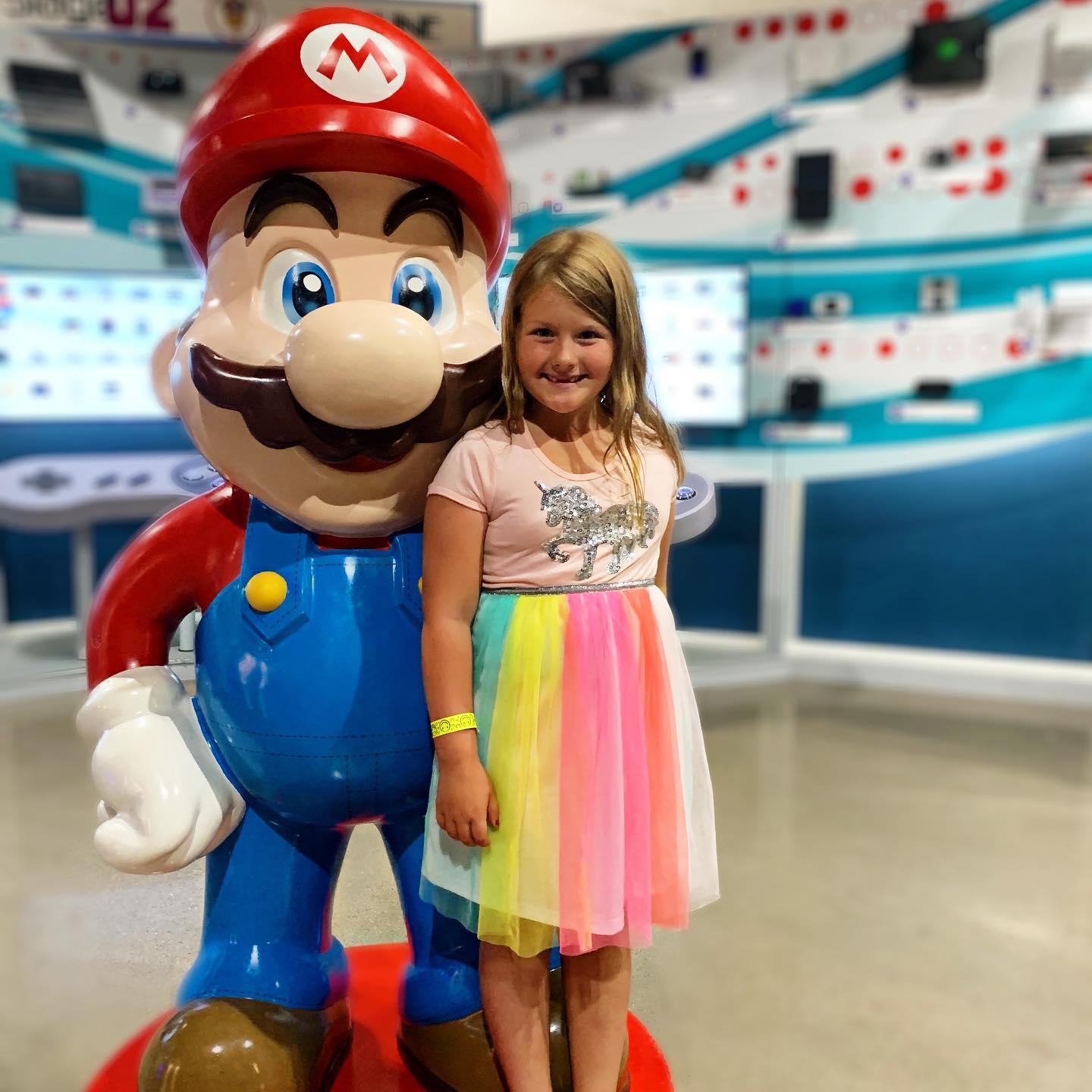 A little girl posing for a photo with Mario