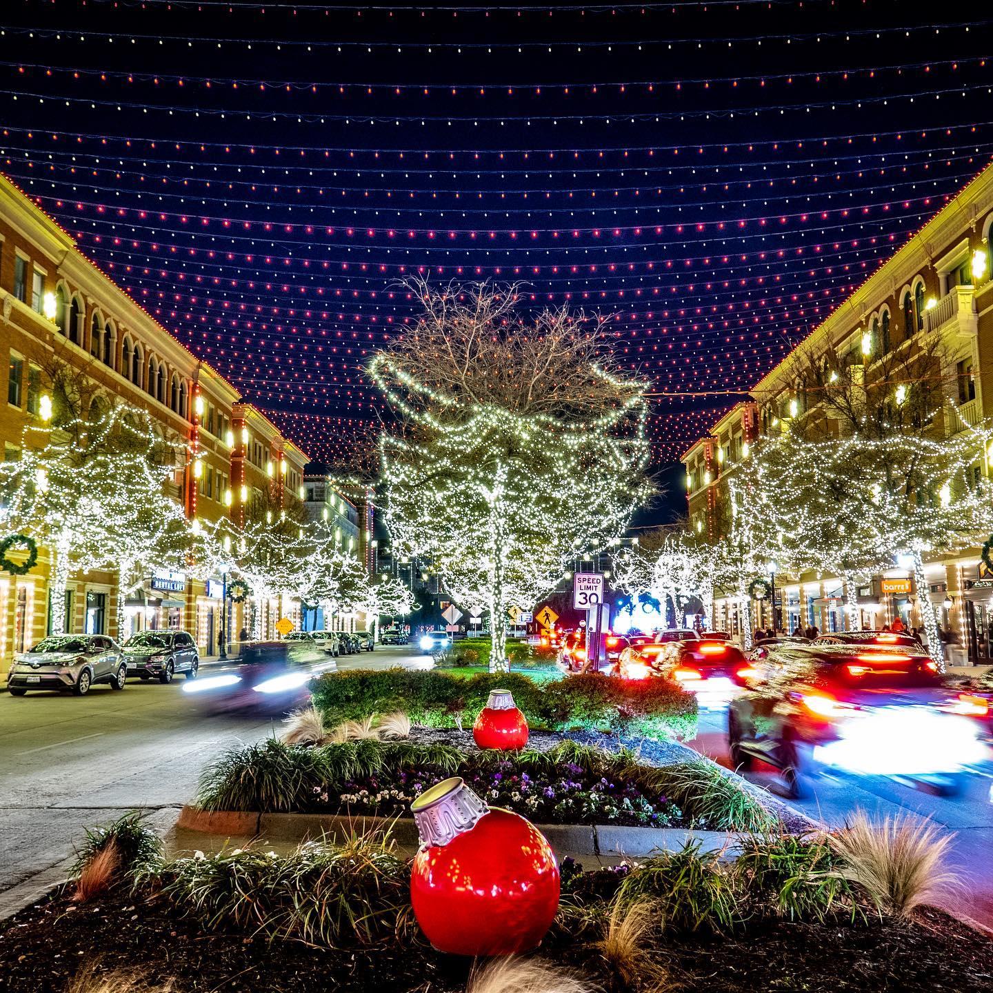 the square lit up with christmas lights and large bauble ornaments