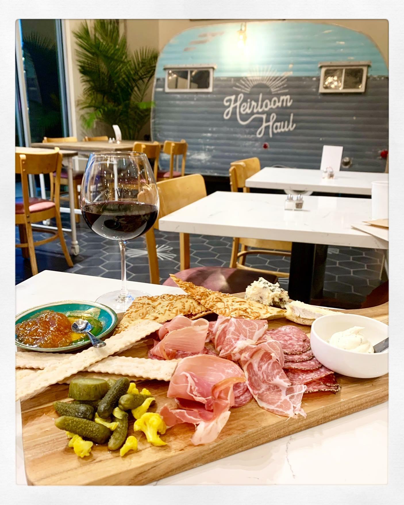 A charcuterie plate with a glass of read wine