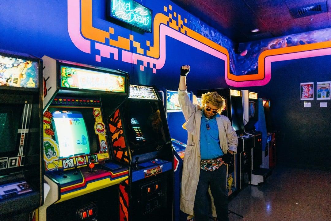 A man fist pumping in an arcade