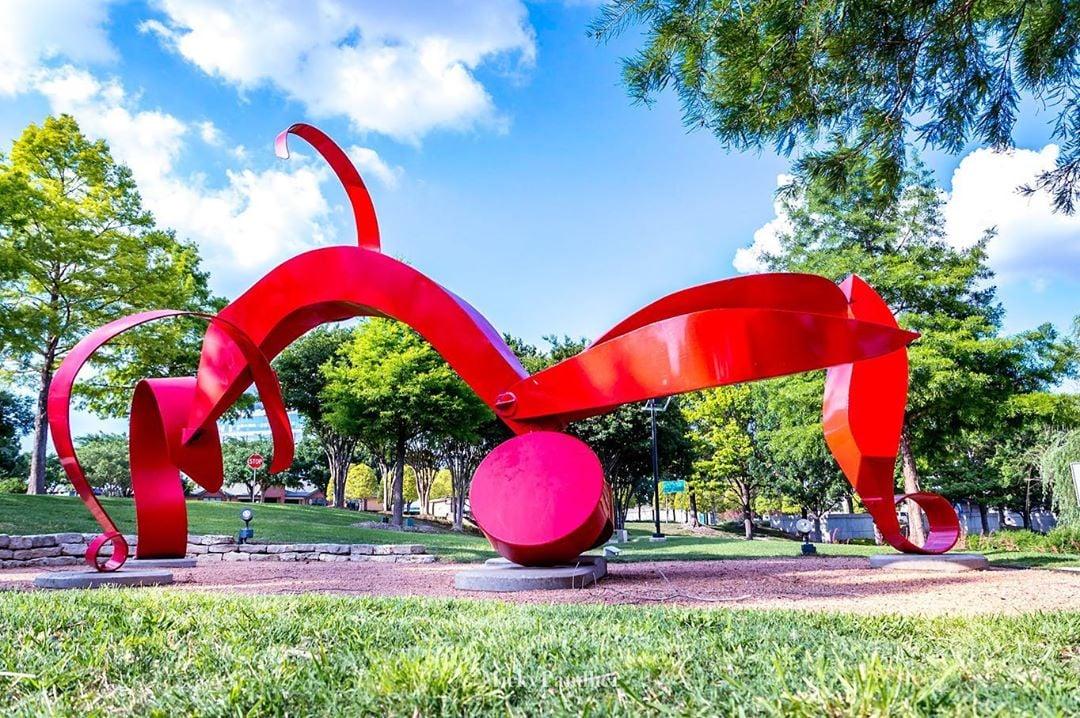 large red metal sculpture in a park
