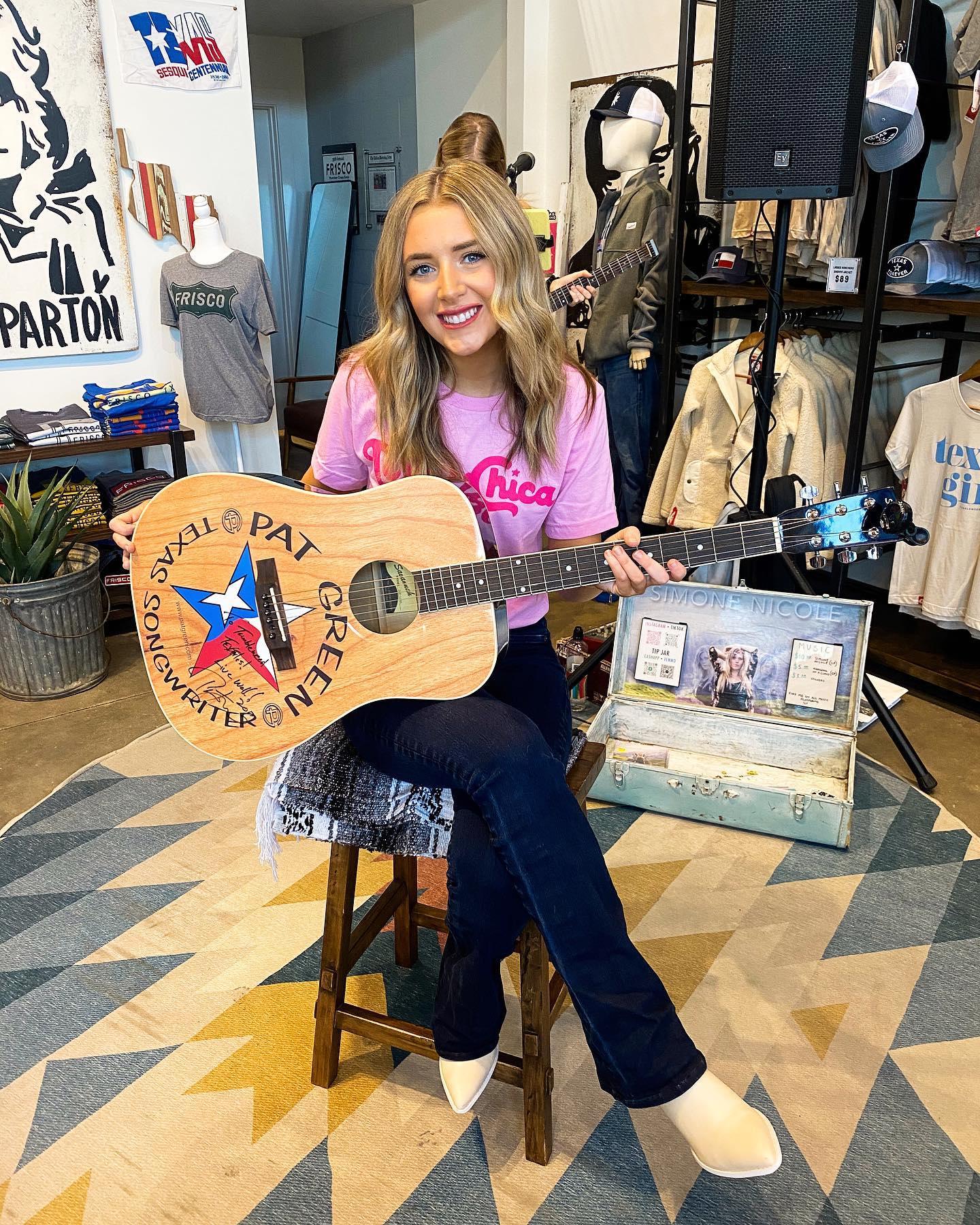 Grace Tyler sitting on a chair with a guitar in her hands